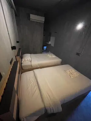 two beds in a small room with a light at Sukhum Rajamangala-Phatthanakan Rooms in Bangkok
