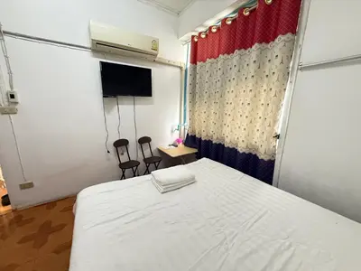 a bedroom with a white bed and two chairs at Happyland Guesthouse in Bangkok