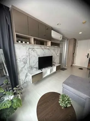 a living room with a television and a marble wall at The Room Sukhumvit 64 Punnawithi in Phra Khanong