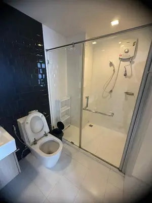 a bathroom with a toilet and a glass shower at The Room Sukhumvit 64 Punnawithi in Phra Khanong