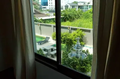 a window with a view of a garden and a patio at Dancenter Sukhumvit 107 Bangkok Hotel in Bangkok