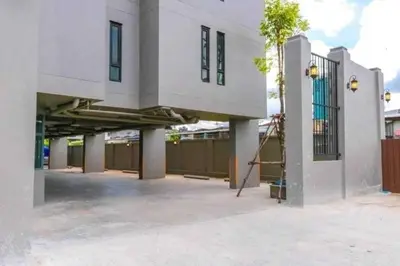 a large white building with a porch and a fence at Dancenter Sukhumvit 107 Bangkok Hotel in Bangkok