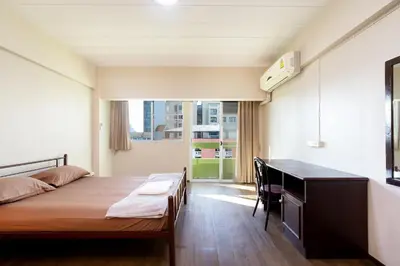 a bedroom with a bed and a desk and a window at Petch Tower Ekamai Budget Serviced Apartments in Bangkok