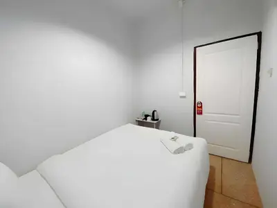 a white bedroom with a white bed and a door at XX The Hidden khaosen เดอะ ฮิดเด้น ตรอกข้าวสาร in Bangkok