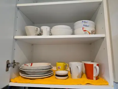 a cupboard filled with plates and mugs and bowls at Fully equipped Ideo Rama9-Asoke, with workstation in Bangkok