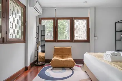a bedroom with a bed and a chair and windows at MIQ S22 Pool Villa PhromPhong Emsphere 5BR in Bangkok