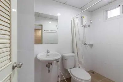 a white bathroom with a toilet and a sink at Townhouse Siam Privi Hotel in Bangkok