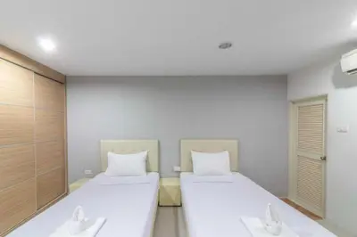 two beds in a room with white walls at Townhouse Siam Privi Hotel in Bangkok