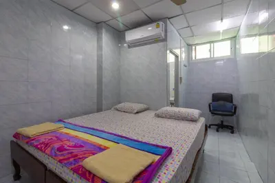 a small bedroom with a bed and a chair at New Central Guesthouse in Bangkok