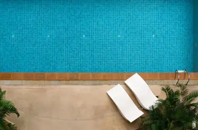 two white chairs sitting next to a swimming pool at Spacious 2 King Beds, Balcony with View, Near Nana BTS in Bangkok