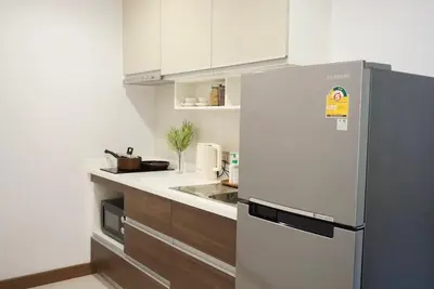a kitchen with a stainless steel refrigerator and wooden cabinets at Amazing Pool and Luxury Condo Unit Near Phrom Phong BTS in Bangkok