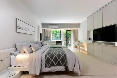 a white bedroom with a large bed and a flat screen tv at Tree Villa Bangkok in Bangkok