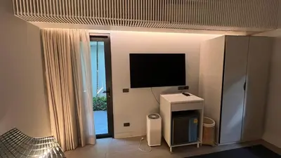 a living room with a flat screen tv on the wall at Tree Villa Bangkok in Bangkok