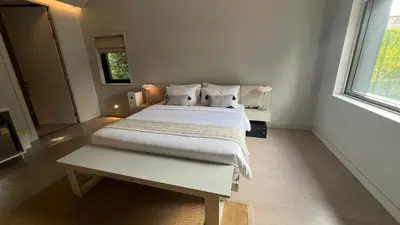a white bedroom with a large bed and a window at Tree Villa Bangkok in Bangkok