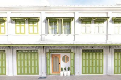 a white building with green doors and windows at Kraft Haus in Khlong San