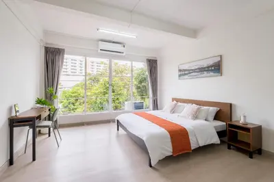 a bedroom with a bed and a desk and a window at Glow House Sukhumvit 54 in Bangkok
