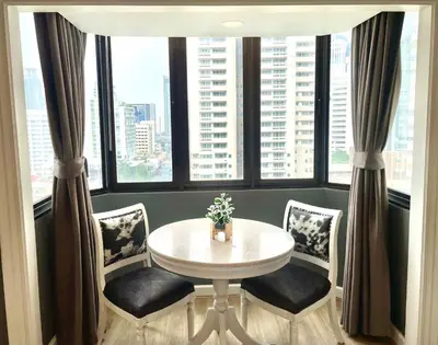 a table and chairs in a room with large windows at Vibrant City Retreat 6 Mins Walk BTS Nana, 1BR in Bangkok