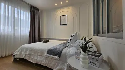 a bedroom with a bed with a table and a window at Easy Living in Bang Khen