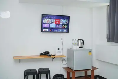 a tv hanging on a wall with a refrigerator and stools at GO Inn Rama 3 BKK - โกอินน์ พระราม 3 in Bang Khlo