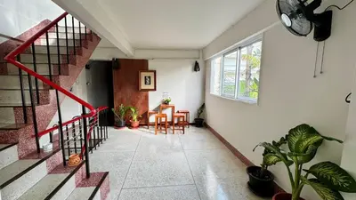 a hallway with stairs and a table and chairs at Baan PadSeeEw - Rooftop Riverview 2nd floor in Thonhuri