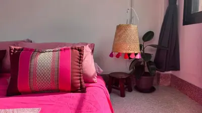a bedroom with a bed with a pink blanket and a lamp at Baan PadSeeEw - Rooftop Riverview 3rd floor in Thonhuri