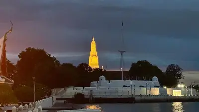 a large building with a lit up tower in the background at Baan PadSeeEw - Rooftop Riverview 3rd floor in Thonhuri