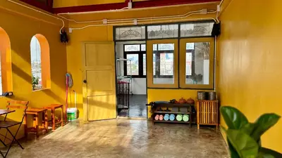 a yellow room with a door and a table and chairs at Baan PadSeeEw - Rooftop Riverview 3rd floor in Thonhuri