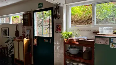 a kitchen with a green door and two windows at Baan PadSeeEw - Rooftop Riverview 4th floor in Thonhuri