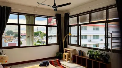 a living room with windows with a view of a building at Baan PadSeeEw - Rooftop Riverview 4th floor in Thonhuri