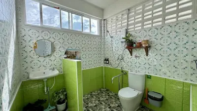 a green bathroom with a toilet and a sink at Baan PadSeeEw - Rooftop Riverview 4th floor in Thonhuri