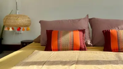 a bed with colorful pillows on top of it at Baan PadSeeEw - Rooftop Riverview 4th floor in Thonhuri