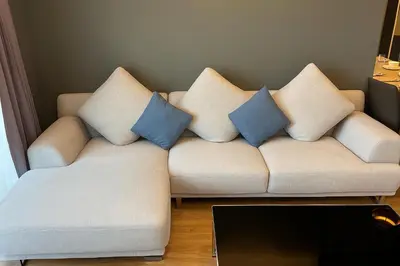 a white couch with three blue pillows on it at Alcove 53 in Bangkok