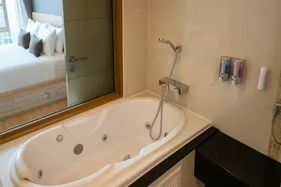 a bath tub in a bathroom with a large mirror at Alcove 53 in Bangkok