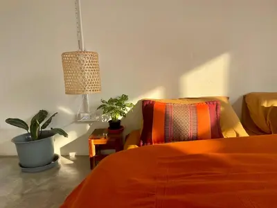a bedroom with an orange bed and a potted plant at Baan KhaoSoi - Rooftop House in Talad Noi in Samphanthawong