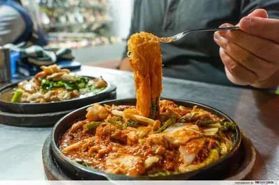 a person eating a plate of food with a fork and pasta at Cozy Canal House 1 min to MRT & Street Foods in Bangkok