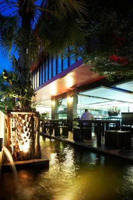 a building with a palm tree in front of a river at Diamond Residence Ratchada in Bangkok