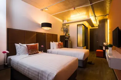 a hotel room with two beds and a television at Aim House Bangkok No Parking in Bangkok