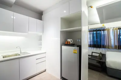 a kitchen with white cabinets and a refrigerator at Aim House Bangkok No Parking in Bangkok