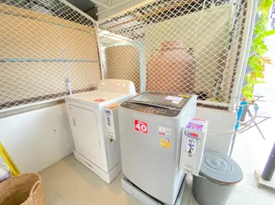 a small room with a washing machine and a trash can at Kudi Hostel in Bangkok