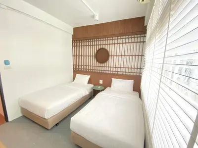 two beds in a small room with a window at Kudi Hostel in Bangkok