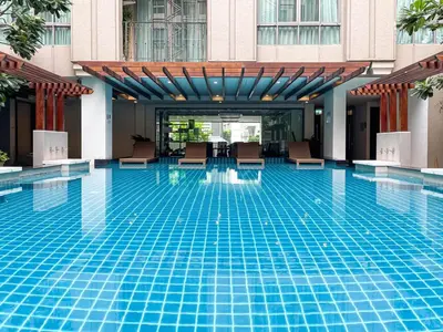 a swimming pool with chairs in a building at Comfortable Stay 1BR - Ultra Fast Wifi - Huai Khwang in Bangkok