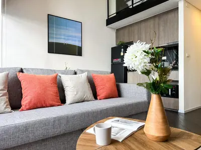a living room with a gray couch with orange and white pillows at Elegant 1BR Condo - Ultra Fast WiFi - BTS On-Nut in Bangkok