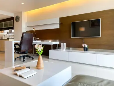 a living room with a television on a wall at Spacious City 118 SQM Fast WiFi BTS Chong Nonsi in Bangkok