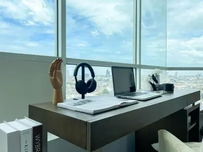 a desk with a laptop and headphones on a window at Spacious City 118 SQM Fast WiFi BTS Chong Nonsi in Bangkok