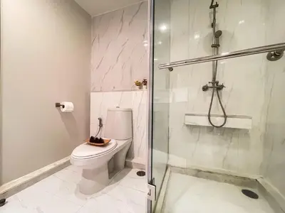 a bathroom with a toilet and a glass shower at Spacious City 118 SQM Fast WiFi BTS Chong Nonsi in Bangkok