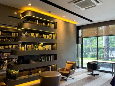 a library with bookshelves and chairs and a table at Cozy Park-view 1BR - Ultra Fast Wifi - BTS Bangna in Bangkok