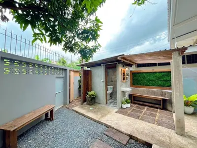 a backyard with a wooden bench and a house at Entire House 3BR - White and Green Guesthouse in Bangkok Yai