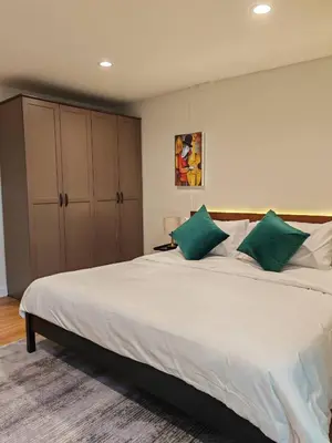 a bedroom with a large white bed with green pillows at Super cozy new townhome in central of Bangkok 4 PAX in Ban Chek