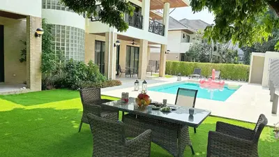 a table and chairs in a yard with a pool at Bangkok Manor Two\u66fc\u8c37\u8d30\u53f7\u5e84\u56ed in Bangkok