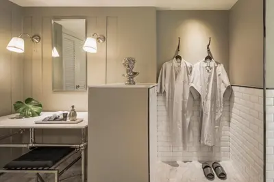 a bathroom with a sink and a shower with robes at Hotel Once Bangkok in Bangkok